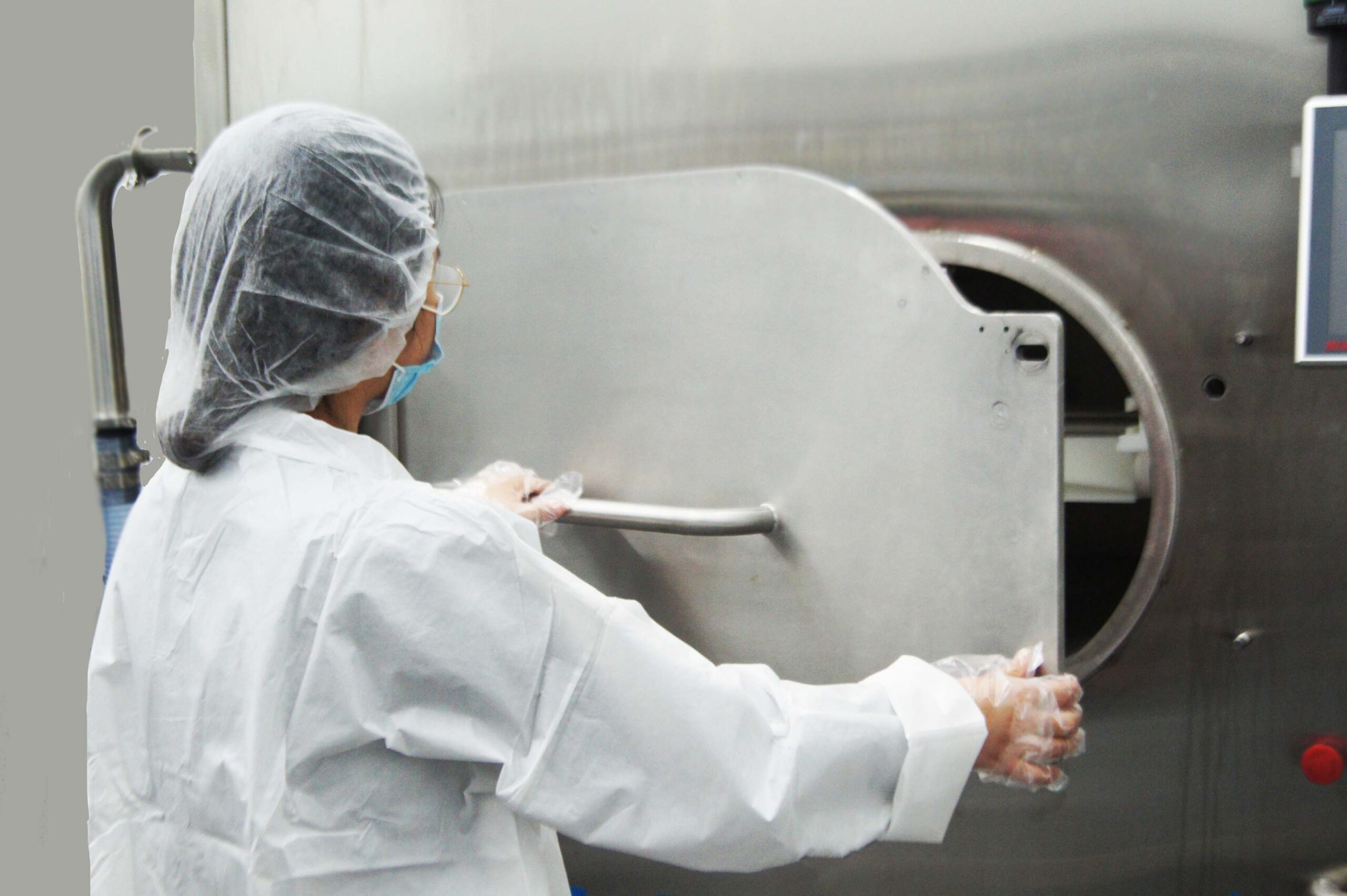 Food scientist closing the door of an industrial microwave system.